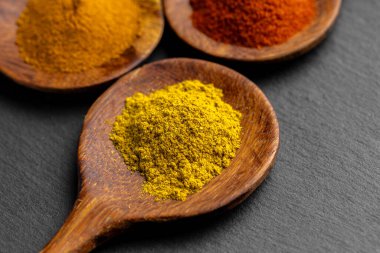 Tahta Kaşıklar Üzerine Renkli Baharatlar Curry, zerdeçal, ve Paprika Karanlık Sayfa Arkaplanda