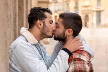 close up of gay couple kissing at street