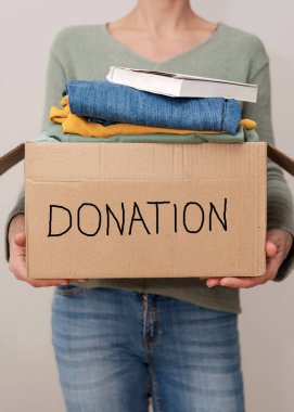 Bağış karton kutusuyla bağış yapan bir kadının dikey görüntüsü.