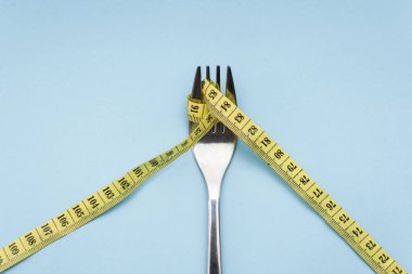 Mavi arka planda sarı şeritli çatal, kilo verme konsepti