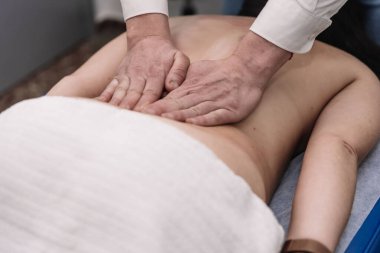 Terapistin elleri hastanın sırtına masaj yapıyor.