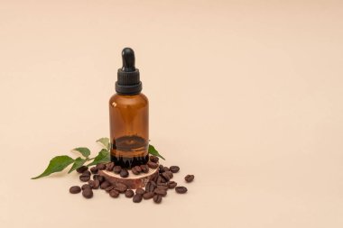 Kahverengi kahve çekirdekleri ve yeşil yapraklarla çevrili kehribar şişesi bej arka planda, doğal cilt bakımı ya da temel yağ kavramları için mükemmel.