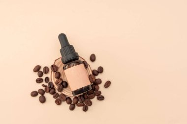 Cam şişe kafein esaslı yağ serumu. Ahşap dilimde boş etiket ve bej arka planda kavrulmuş kahve çekirdekleri.