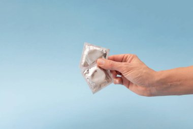 Mavi arka planda iki prezervatif, güvenli seks ve HIV önleme