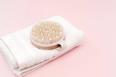 Beyaz bir havluda dinlenen doğal ahşap ve liften yapılmış kuru fırça, sağlığı ve cilt bakımını teşvik eder.