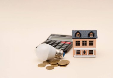 Tarafsız Arkaplan, ev enerjisi tasarrufu ve finansal planlama üzerinde LED ampul, hesap makinesi, madeni para ve minyatür ev