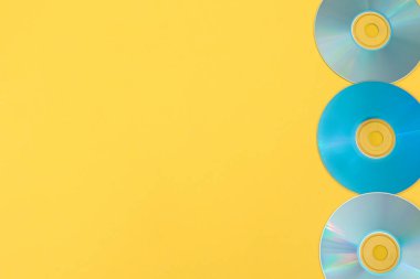 Sarı arkaplanda kopyalama alanı olan üç mavi CD satırı