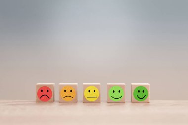 Emojileri gösteren ahşap küpler çeşitli tatmin seviyelerini temsil ediyor, müşteri geribildirimi ve hizmet değerlendirmesini sembolize ediyor