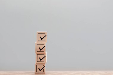 Kontrol işaretleri gösteren dört istiflenmiş tahta küp, olumlu geri bildirim, yüksek hizmet derecesi ve gri bir arkaplana karşı ahşap bir tabloda başarılı bir değerlendirme anlamına gelir.