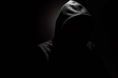 Kapüşonlu bilgisayar korsanı karanlıkta siber saldırı planlıyor, internet güvenlik tehditleri ve siber suç kavramı