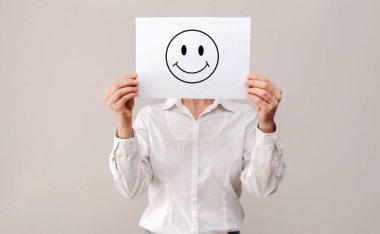 Beyaz gömlekli isimsiz bir kadın beyaz bir kağıt parçasının arkasına saklanıyor.