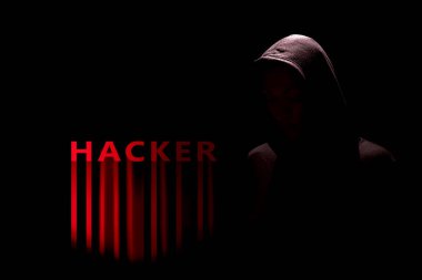 Kırmızı renkli hacker yazısıyla kapüşonlu bir korsanın karanlık silueti.