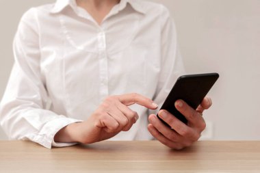 Ofisteki akıllı telefondan internete göz atan kadını kapat.