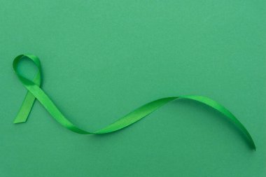 Yeşil farkındalık kurdelesi yeşil arka planda ruh sağlığını simgeliyor.