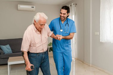 Erkek Fizyoterapist, rehabilitasyon sırasında koltuk değneği kullanan yaşlı bir adama yardım ediyor.