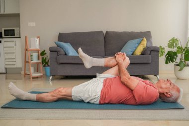 Son sınıf öğrencisi evdeki yoga minderinde bacak esnetme egzersizi yapıyor.