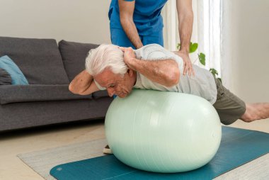Fizyoterapist kıdemli adama evde spor salonunda yardımcı oluyor.