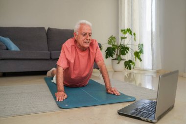 Son sınıf öğrencisi evde dizüstü bilgisayarla yoga yapıyor.