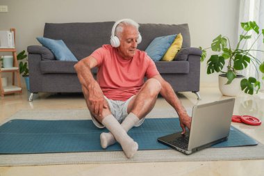 Son sınıf öğrencisi aktif bir yaşam tarzının keyfini çıkarıyor. Evde yoga minderinde dizüstü bilgisayar kullanıyor.