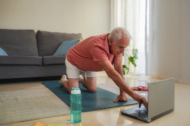 Üst düzey bir adam evde dizüstü bilgisayarla alıştırma yapıyor.