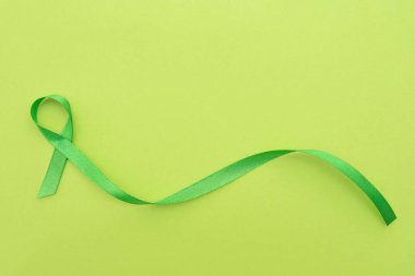 Yeşil farkındalık kurdelesi yeşil ışık arka planında ruh sağlığını simgeliyor.