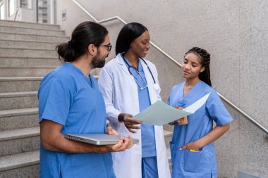 Çok etnik çeşitlilikte tıbbi ekip dışarıda hasta bilgilerini ve tedavi stratejilerini tartışıyor.