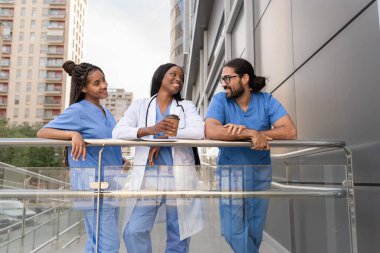 Bir grup çok ırklı doktor ve hemşire hastane dışında kahve molası veriyor.