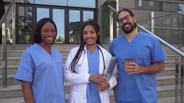 Hastane dışında poz veren mavi üniformalı çok ırklı tıbbi ekibin videosu.