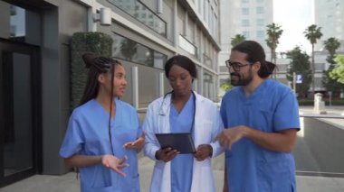 Doktorlar ve hemşirelerin hastanenin dışındaki dijital tablette tıbbi bilgileri incelerken çekilmiş bir video.