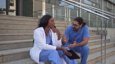 Erkek doktorun kadın meslektaşını hastanenin merdivenlerinde otururken avuttuğunu gösteren bir video.