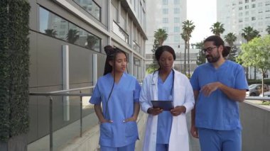 Doktorlar ve hemşirelerin hastanenin dışında bir tablet kullanarak hasta vakalarını tartışmalarını gösteren bir video.