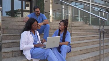 Hastane merdivenlerinde dizüstü bilgisayar kullanan doktorlar ve hemşirelerin tıbbi ekip işbirliği videosu.
