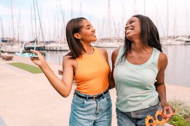 İki çok ırklı bayan arkadaş yaz tatilinin tadını çıkarıyor ve marinada birlikte gülüyorlar.