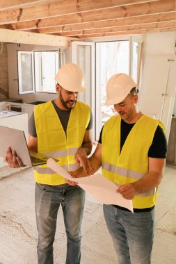 Ev tadilatı sırasında dizüstü bilgisayarı kullanan iki mimar.