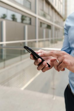 İş adamının ofis binasının dışındaki akıllı telefon uygulamasını kullanarak dikey olarak kapatılması