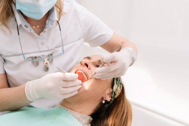 Klinikte dişçi, hastanın dişlerini diş aletleriyle muayene ediyor.