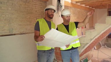 İki inşaat işçisinin projeleri analiz ettiği ve bir inşaat alanında proje detaylarını tartıştığı bir video.