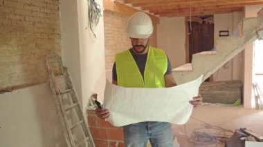 İspanyol inşaatçının veya mühendisin bir inşaat alanının planlarını inceleyen videosu