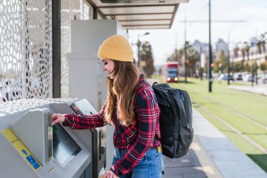 İstasyon bilet makinesinde toplu taşıma ücretini ödeyen genç kız öğrenci