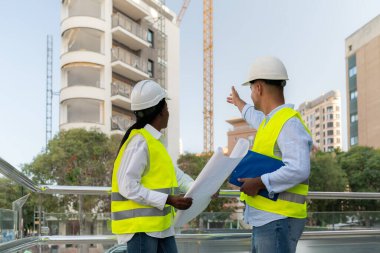 İki farklı güvenlik yelekli mimar şehir şantiyesinde inşaat projesini tartışıyor