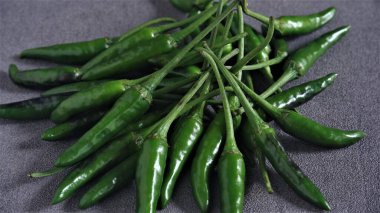 Cayenne. Koyu gri arka planda taze yeşil Cayenne. Capsicum frutescens. Sıcak ve baharatlı. Acı biber ya da kuş gözü kırmızı biber. Endonezya 'da Cabai Rawit olarak da bilinir. Acı biber. Çiğ