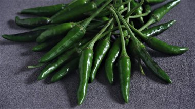 Cayenne. Koyu gri arka planda taze yeşil Cayenne. Capsicum frutescens. Sıcak ve baharatlı. Acı biber ya da kuş gözü kırmızı biber. Endonezya 'da Cabai Rawit olarak da bilinir. Acı biber. Çiğ