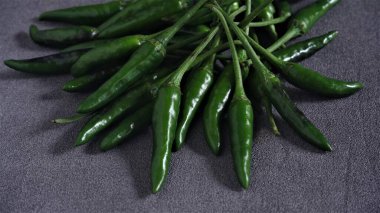 Cayenne. Koyu gri arka planda taze yeşil Cayenne. Capsicum frutescens. Sıcak ve baharatlı. Acı biber ya da kuş gözü kırmızı biber. Endonezya 'da Cabai Rawit olarak da bilinir. Acı biber. Çiğ