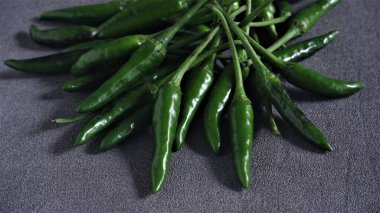 Cayenne. Koyu gri arka planda taze yeşil Cayenne. Capsicum frutescens. Sıcak ve baharatlı. Acı biber ya da kuş gözü kırmızı biber. Endonezya 'da Cabai Rawit olarak da bilinir. Acı biber. Çiğ