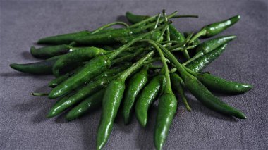 Cayenne. Koyu gri arka planda taze yeşil Cayenne. Capsicum frutescens. Sıcak ve baharatlı. Acı biber ya da kuş gözü kırmızı biber. Endonezya 'da Cabai Rawit olarak da bilinir. Acı biber. Çiğ