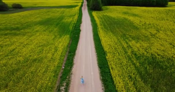 Mulher Loira Correndo Com Vestido Azul Lado Campo Colza Amarelo — Vídeo de Stock