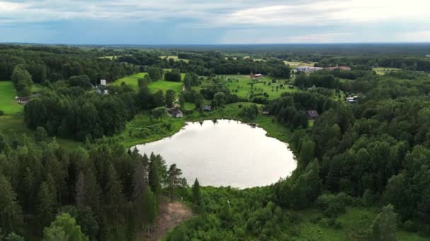 丸い形の湖を飛んでいます 夏の夜 背景に暗い雲 田舎の家だ 夏の気分だ 緑の森と木々 青い色の湖 そうだ 高品質4K映像 — ストック動画