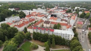 4K hava görüntüleri eski kasabanın üzerinde. Estonya, Tartu. Kilisenin kulesi. Bir meydanın önündeki katedral, kamerayla yukarı doğru eğiliyor. Kırmızı çatılar. Yeşil şehir. Güzel seyahat yeri