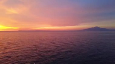 Napoli, İtalya, Vesuvios Dağı. Gün batımının renkleri dağlara yansıyor. Kayalık kayalıklarda kırmızı ve turuncu renkler var. Tyrhenian denizi ve Vezüv Yanardağı. Zaman aşımı, aşırı hız. 