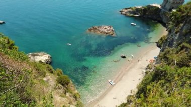 Özel bir sahil manzarası. Kuşlar uçuyor. Küçük dalgaların üzerindeki hava manzarası sahile çarpıyor. Mavi şeffaf tropikal kayalık sahil şeridi. Dağlık lüks plaj. Beyaz kum. Altın plaj